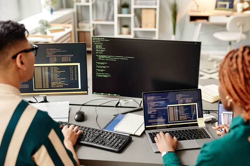 Image of two developers as a table with computers working with test data management tools.