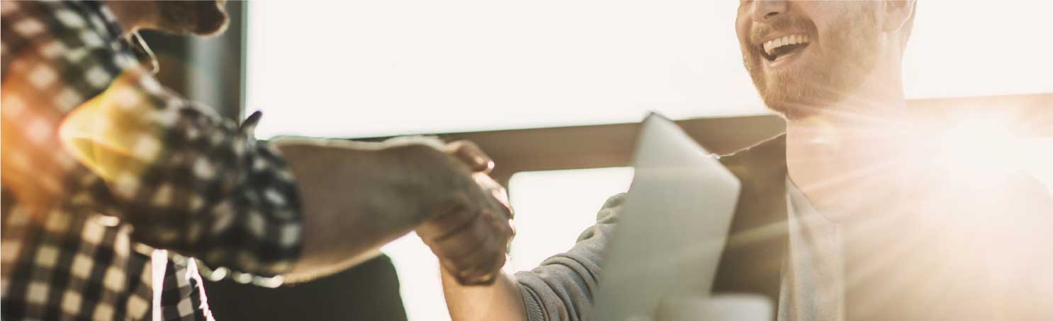 Two people share a smile and a handshake at sunset
