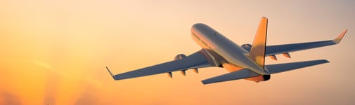 Plane taking off into sky at sunset