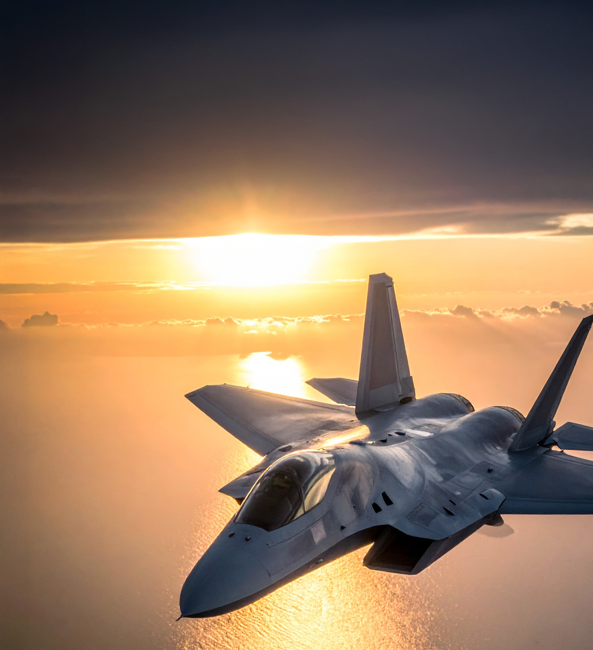 Un avión F-35 vuela durante la puesta de sol sobre el mar.