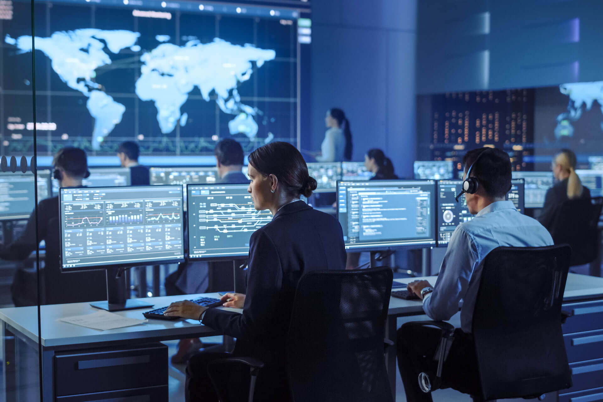 Government office with multiple people working on computers with headsets on examining data